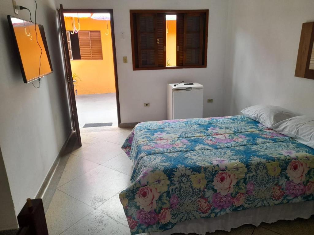 a bedroom with a bed with a quilt on it at HOTEL GUARAREMA in Guararema