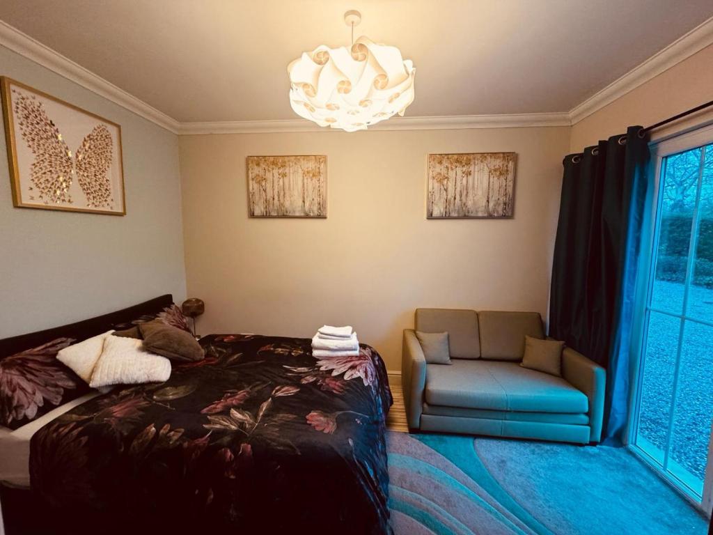 马奇Adorable one-bed place in Cambridgeshire的一间卧室配有一张床、一把椅子和一个吊灯。