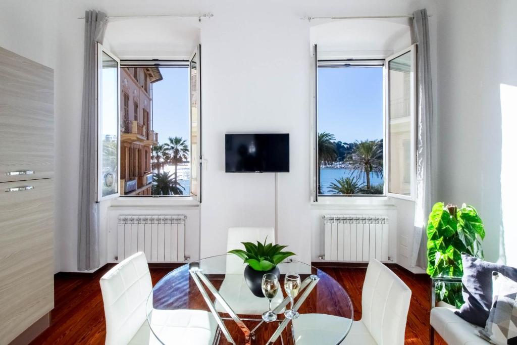 ein Esszimmer mit einem Glastisch und weißen Stühlen in der Unterkunft Butterfly Apartment in Rapallo