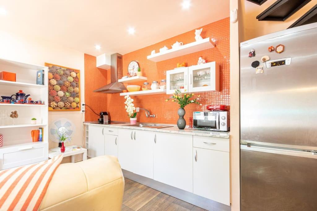 una cocina con armarios blancos y una pared de color naranja en TRA9-CASA con BARBACOA, PISCINA comunitaria en verano, 5 min en coche del MAR y el CENTRO, en Empuriabrava