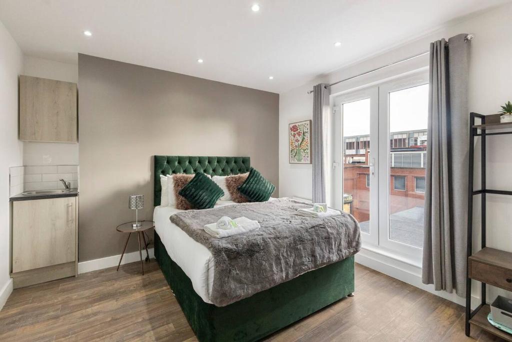a bedroom with a large green bed with a window at Cosy Studio Perfect For Two in Hanwell