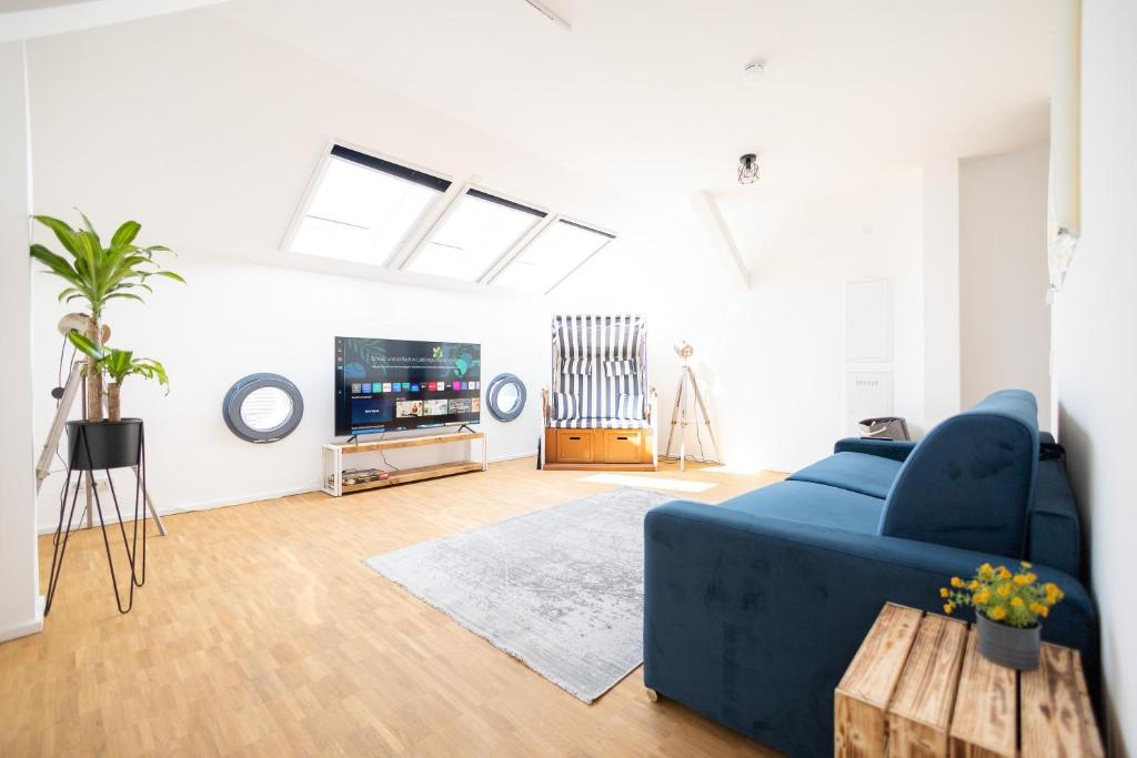uma sala de estar com um sofá azul e uma televisão em Ko-Living - Captain's Suite - Altstadt - mit Küche, Smart TV & Balkon - 6P em Halle an der Saale