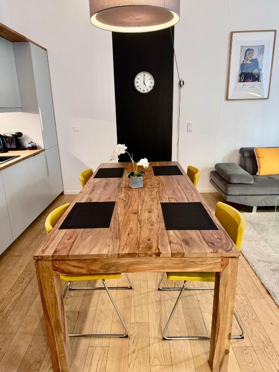- une table en bois avec des chaises jaunes dans le salon dans l'établissement Vieil Antibes Apartment with AC 320m from Beach, à Antibes