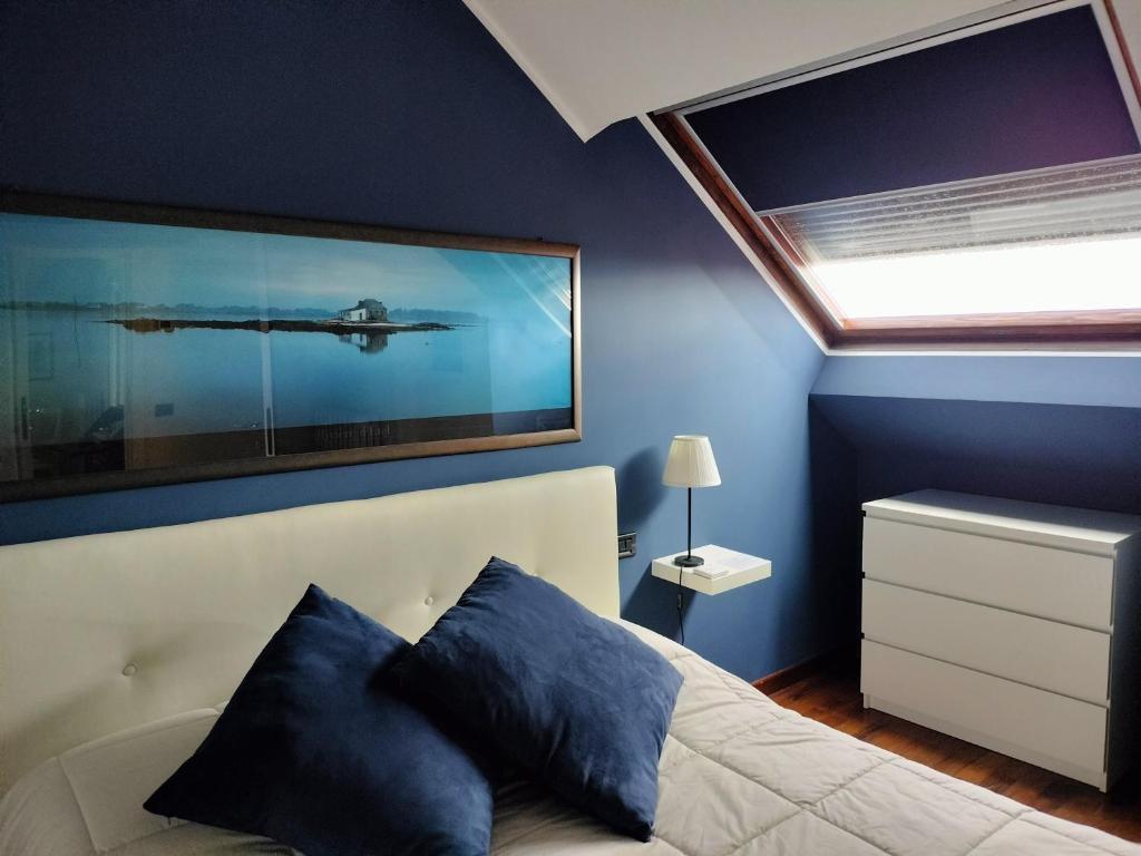 una camera da letto con pareti blu e un letto con cuscini blu di Mansarda DaSy ad Ancona