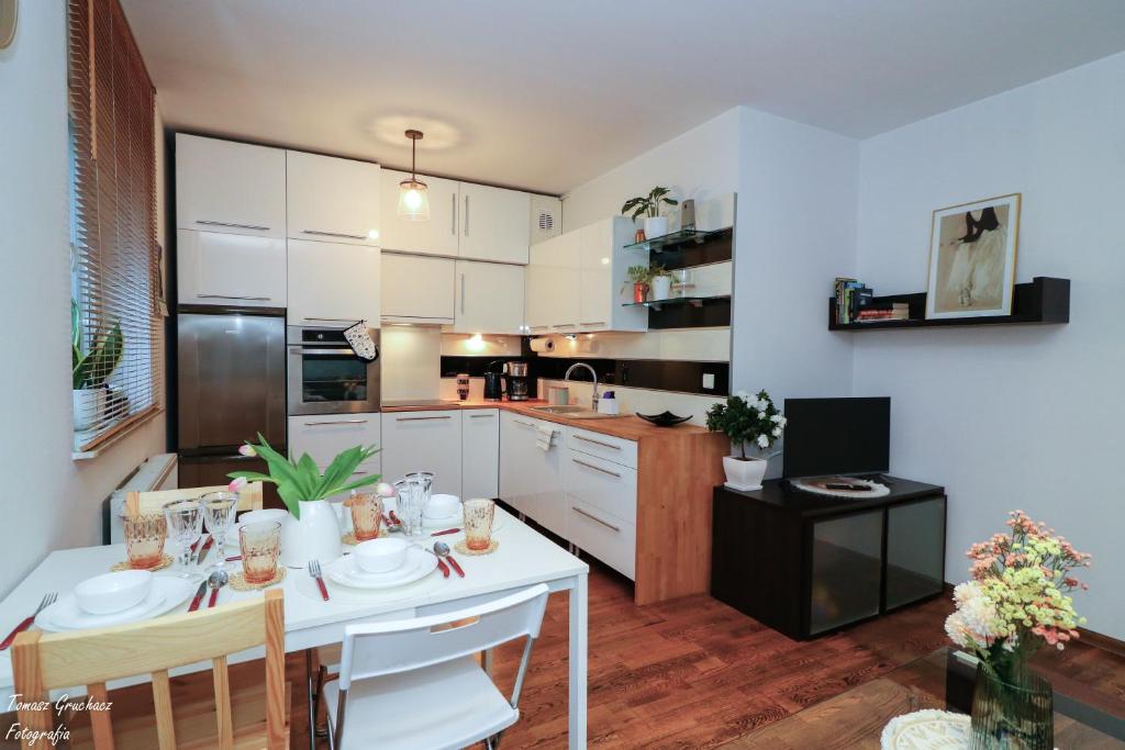 una cocina con armarios blancos y una mesa y sillas blancas. en Apartament Działkowa przy Parku, en Chorzów