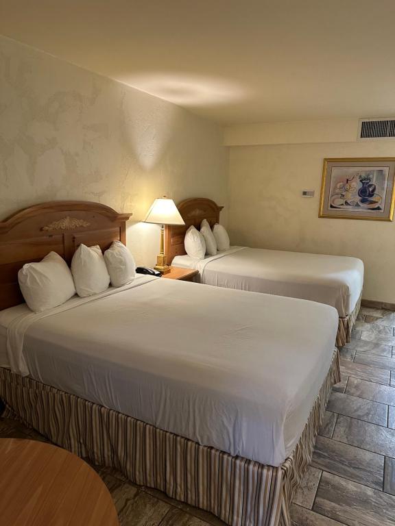 a hotel room with two beds and a lamp at Ramada by Wyndham Las Cruces Hotel & Conference Center in Las Cruces