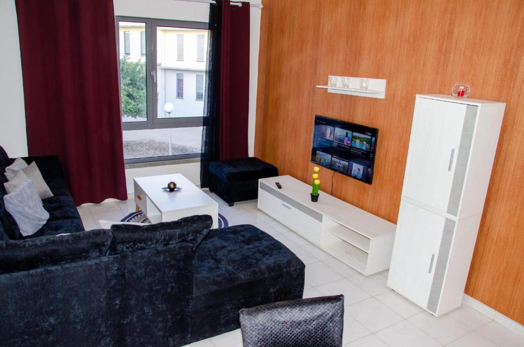 a living room with a couch and a tv at Apartamento T2 Equipado e Aconchegante. in Praia