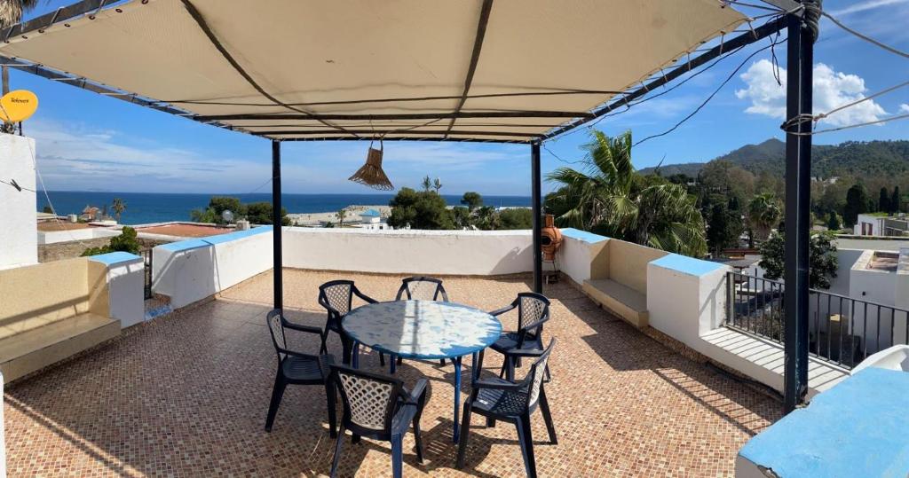 eine Terrasse mit einem Tisch und Stühlen auf dem Balkon in der Unterkunft Appartement vue sur mer Résidence Marsa M’diq in Mʼdik