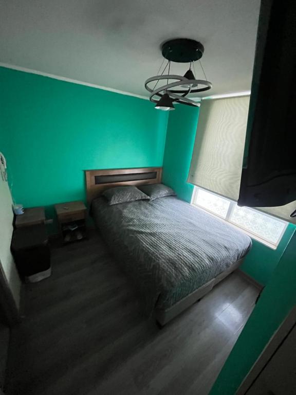 zieloną sypialnię z łóżkiem i zieloną ścianą w obiekcie Departamento Avenida tobalaba w mieście Santiago