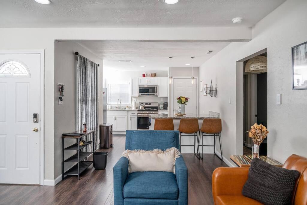 a living room with a blue chair and a kitchen at Remodeled Home w/ King Bed, Bunk Bed, & Yard Games in Concord