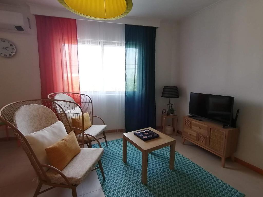 een woonkamer met een tv en stoelen en een tafel bij Sweet Calhetas in Ribeira Grande