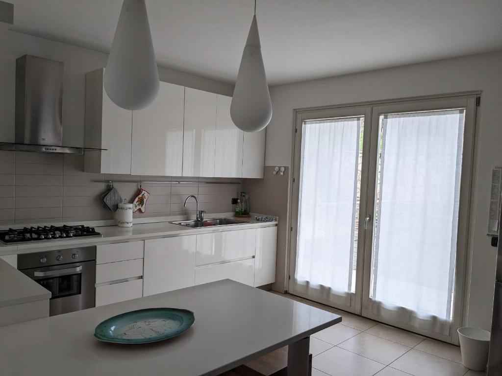 une cuisine avec des placards blancs et une table avec une plaque de cuisson. dans l'établissement La Terrazza su Trento: vista e relax, à Trente