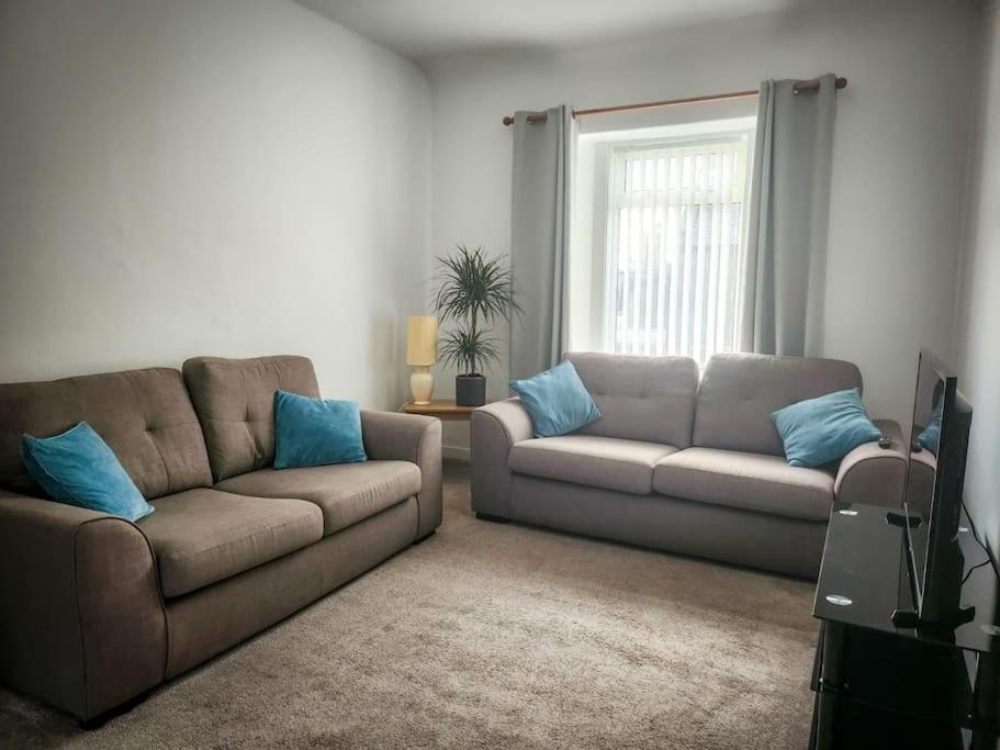 a living room with a couch and blue pillows at Central 2-bedroom bunglow with double sofa bed in Carnoustie