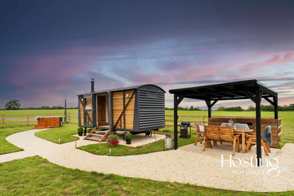 One Of A Kind Shepherds Hut With Incredible Views في تايم: منزل صغير مع طاولة وشرفة