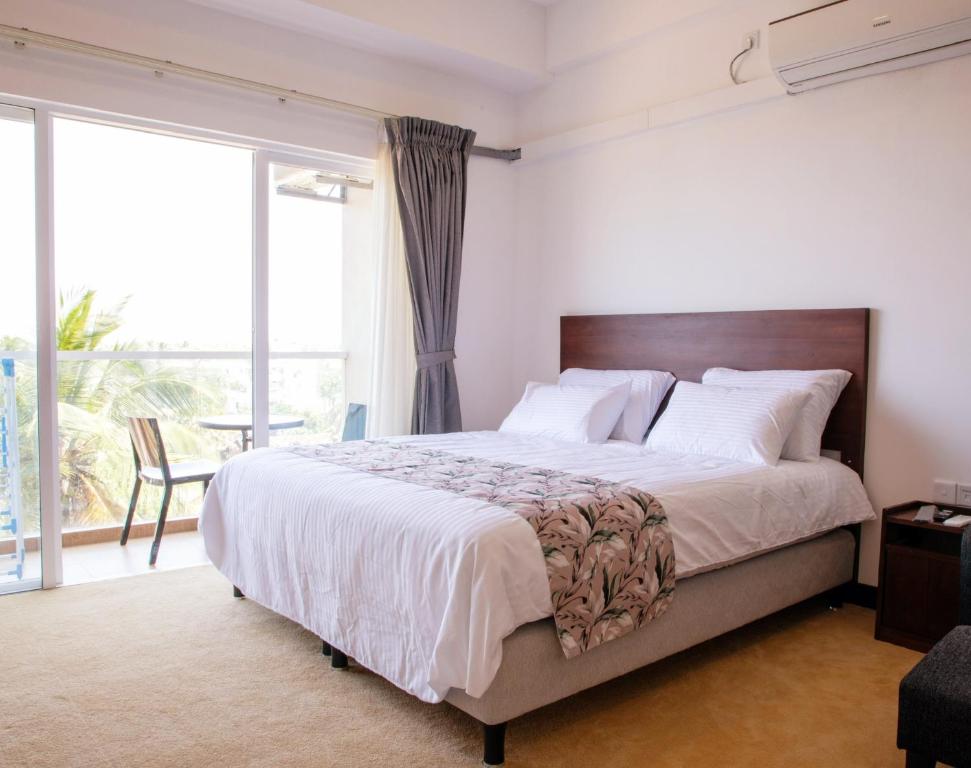 Ocean Breeze Apartment Negombo, R 5, B16 Mina في نيجومبو: غرفة نوم بسرير كبير ونافذة كبيرة