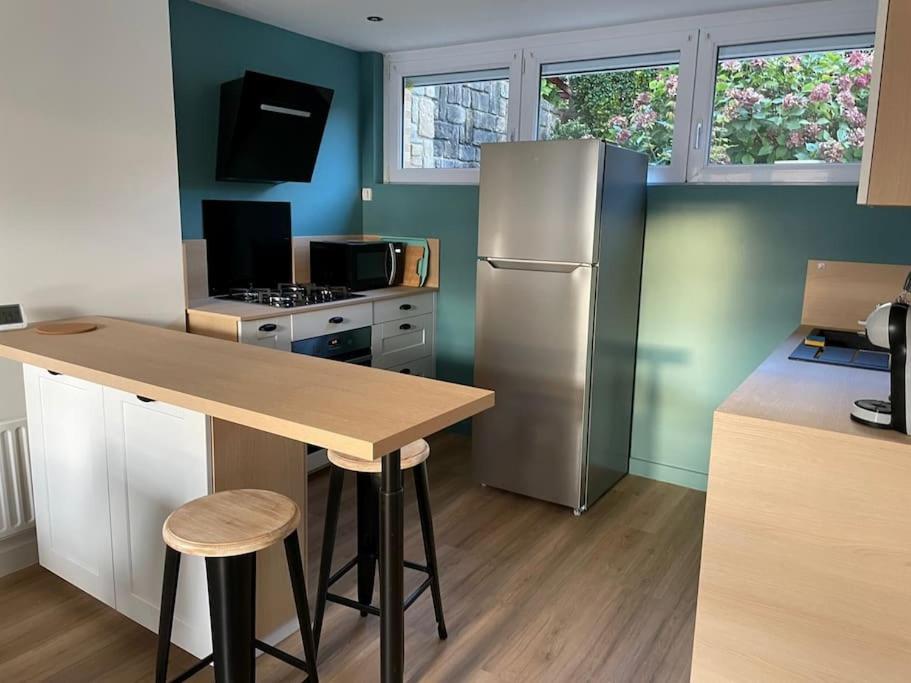 een keuken met een koelkast en een tafel met krukken bij Jolie maison à Equihen-Plage in Équihen-Plage