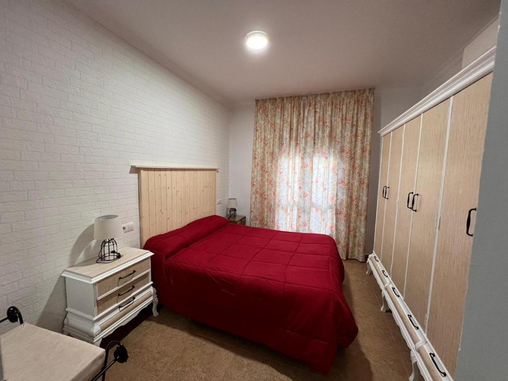 a bedroom with a red bed and a window at Apartamentos Virgen de Villaverde in Ardales