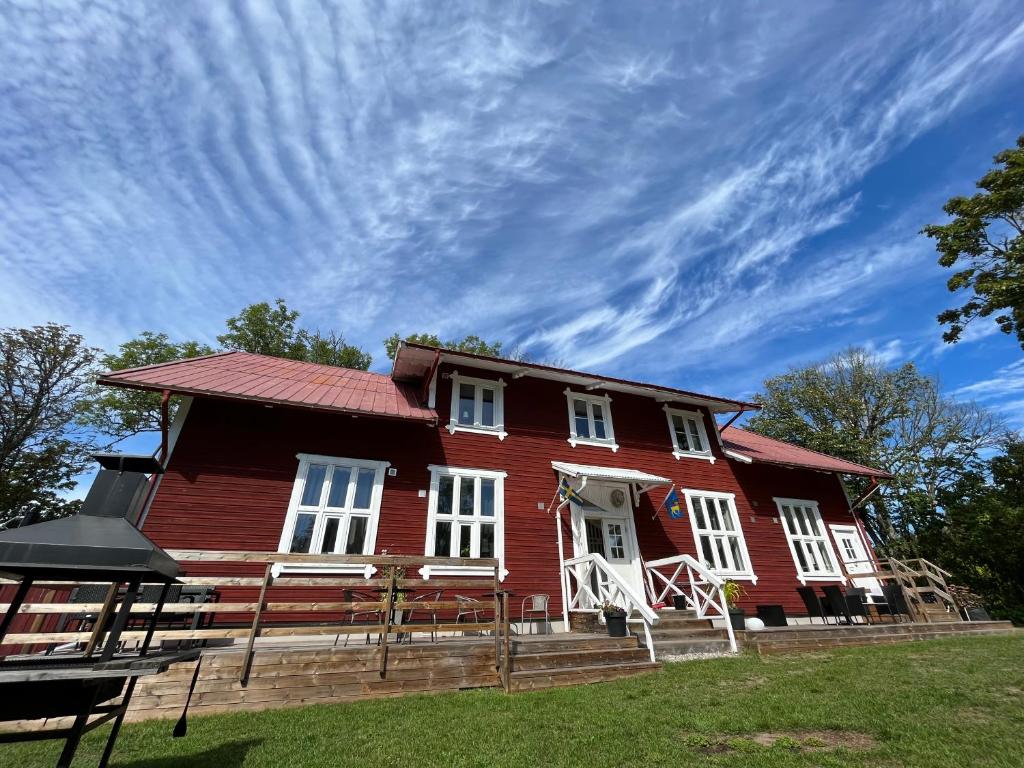 een rood huis met witte ramen en een bewolkte hemel bij Villa Högby in Löttorp