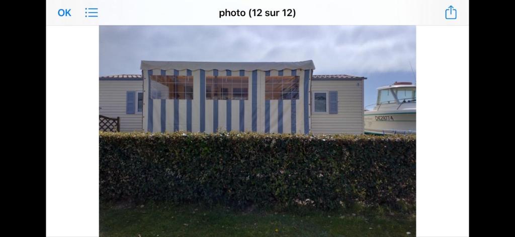 une photo d'une maison avec un bateau derrière une haie dans l'établissement mobil loc a la semaine, à Portbail