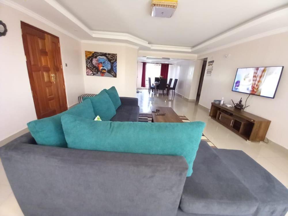 FH apartments opposite culture mambo في ناكورو: غرفة معيشة مع أريكة وطاولة