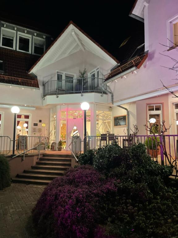 a white house with stairs and purple flowers at Castell Hotel & Restaurant in Leinsweiler