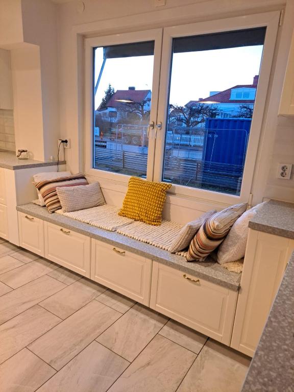eine Bank in einem Zimmer mit zwei großen Fenstern in der Unterkunft Lägenhet på Rosenlund in Jönköping