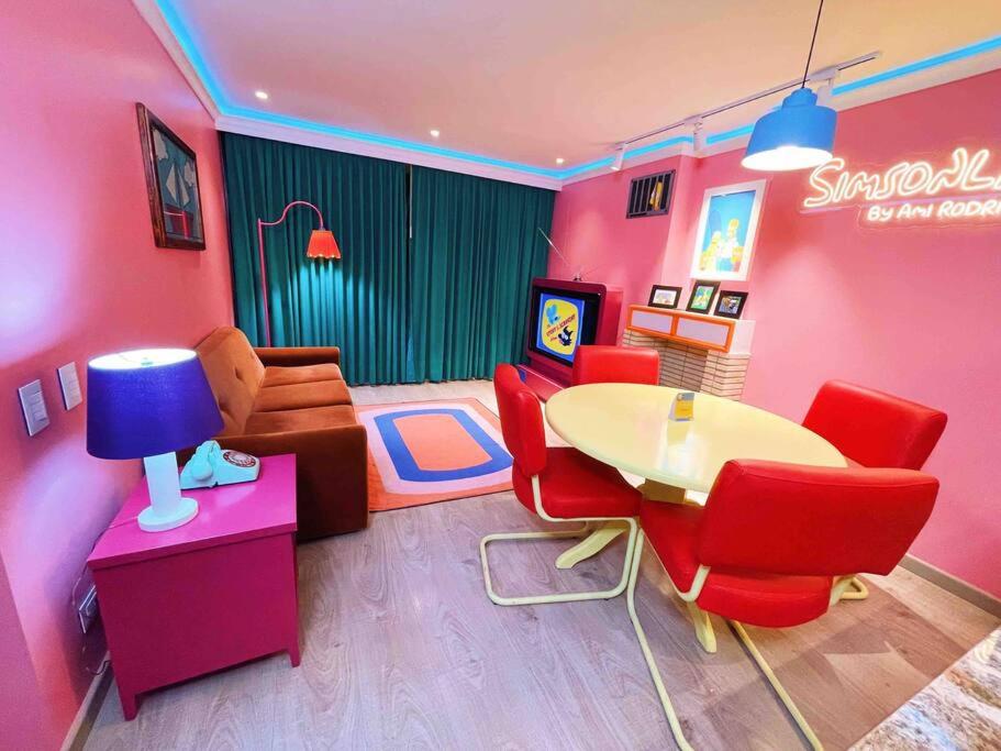 een kamer met een roze kamer met een tafel en stoelen bij Simsonlandia, el apartamento más cool in Bogota