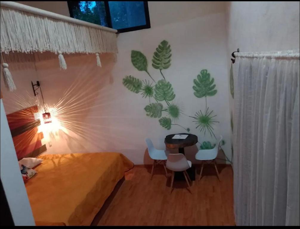 um quarto com uma cama e cadeiras e uma parede com plantas em Aldea Kinich em Tulum