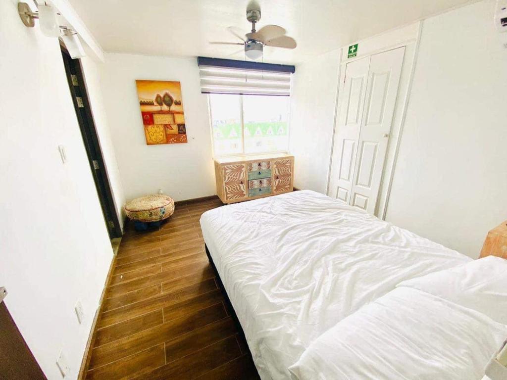 ein Schlafzimmer mit einem weißen Bett und einem Fenster in der Unterkunft San Andrés exotic in Bogotá