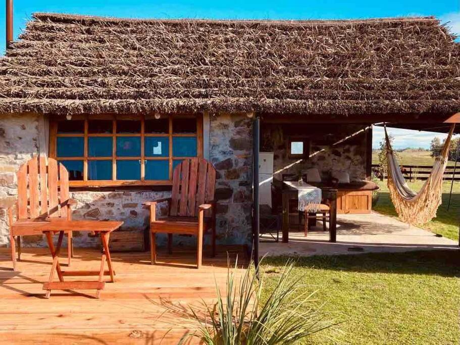 dom z dwoma krzesłami i stołem przed nim w obiekcie Quincho Nativo w mieście Tacuarembó