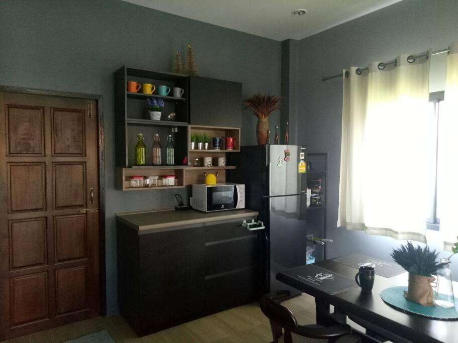 a kitchen with a refrigerator and a table and a microwave at Happy home Suratthani 152/57 in Amphoe Koksamui