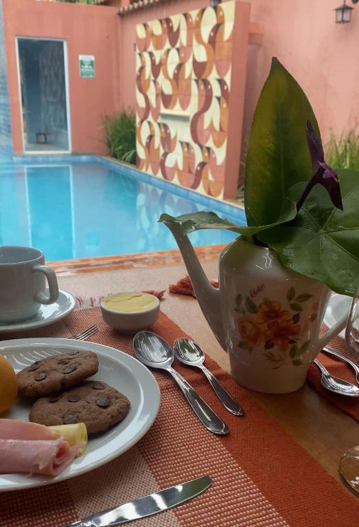 a table with a plate of cookies and a vase at Pousada Mãe Natureza in Pirenópolis