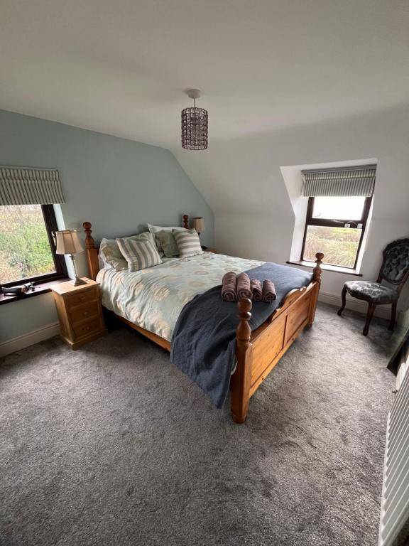 um quarto com uma cama grande e 2 janelas em Seaview House Reenard South em Cahersiveen