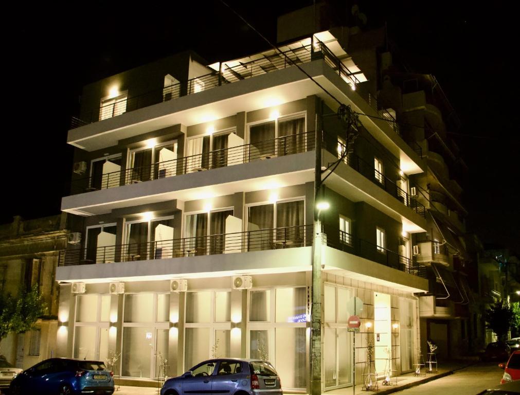 een wit gebouw met twee auto's ervoor geparkeerd bij Piraeus Relax in Piraeus