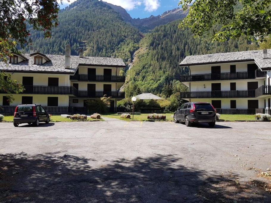 two cars parked in a parking lot in front of a building at Appartamento Valdobbia in Gressoney-Saint-Jean