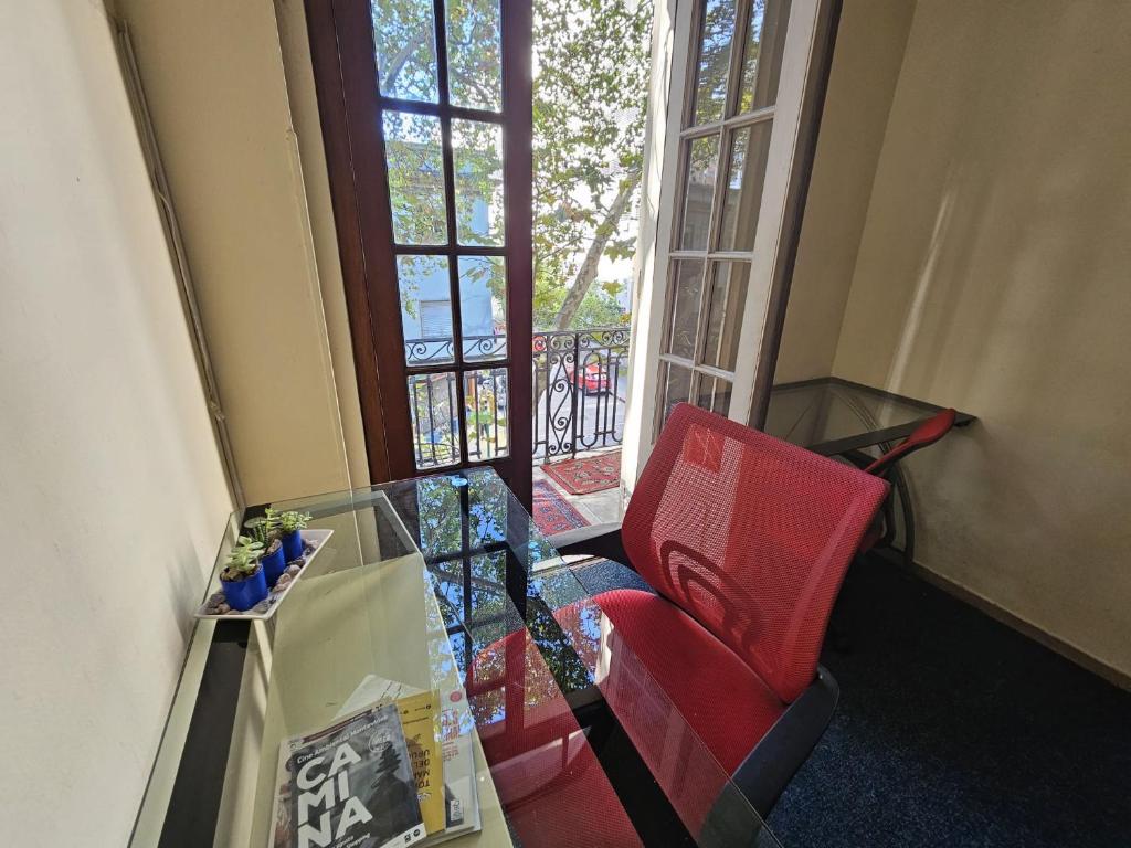 Habitación con mesa de cristal y silla roja. en Montevideo Hostel, en Montevideo