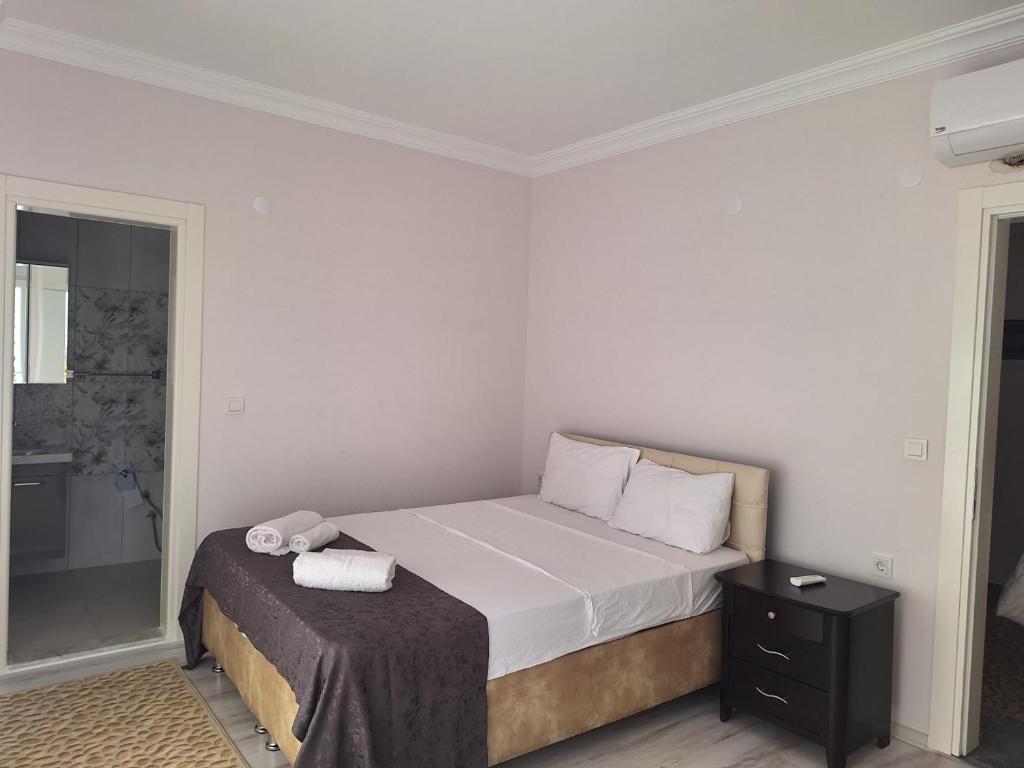 a bedroom with a bed with a black nightstand and white sheets at VİLLA BELİNAY in Belek