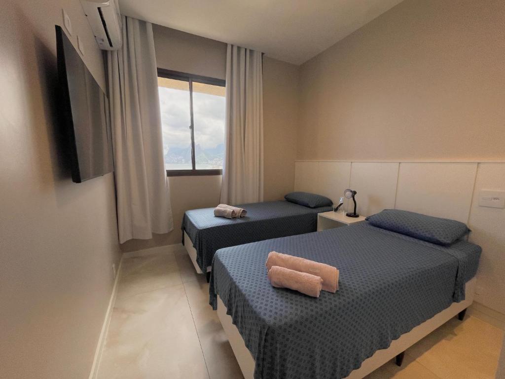 リオデジャネイロにあるArpoador Vista Marのベッド2台と窓が備わる小さな客室です。