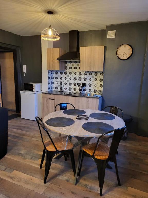 einen Tisch und Stühle in einer Küche mit einer Uhr an der Wand in der Unterkunft Appartement rénové in Leffrinckoucke