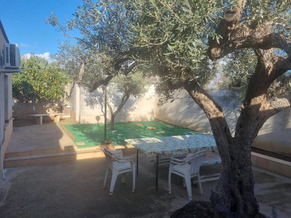 una mesa y sillas bajo un árbol en un patio en Villa Serroni, en Mazara del Vallo