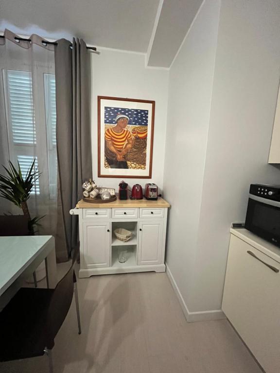 a kitchen with a white cabinet and a picture on the wall at Prato Home - apartment near the beach in Menton in Menton