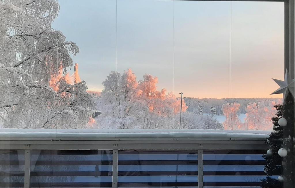 een uitzicht op een vuur vanuit een raam met sneeuw bij RIVER VIEW & CENTRAL LOCATION - private sauna & glazed balcony in Rovaniemi
