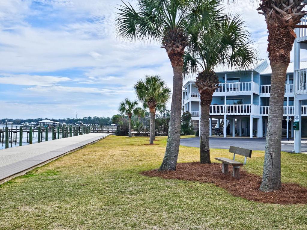 a park with palm trees and a bench in front of a building at Bring Your Boat! 2br/2ba Condo on the Bay! in Orange Beach