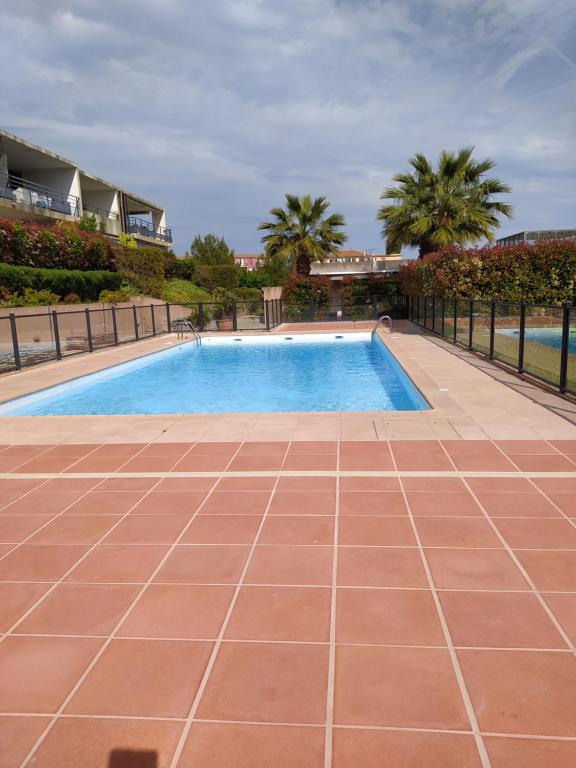 a swimming pool with a tile floor next to a fence at Bel Azur in Saint-Laurent-du-Var