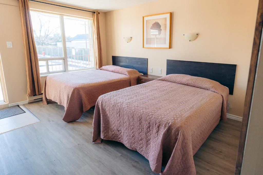 a hotel room with two beds and a window at Clarkson Village Motel in Mississauga