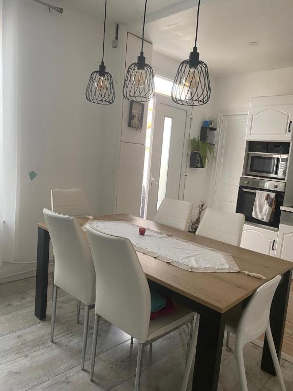 a kitchen with a wooden table and white chairs at maison a louer pour le jeux olimpique in Melun