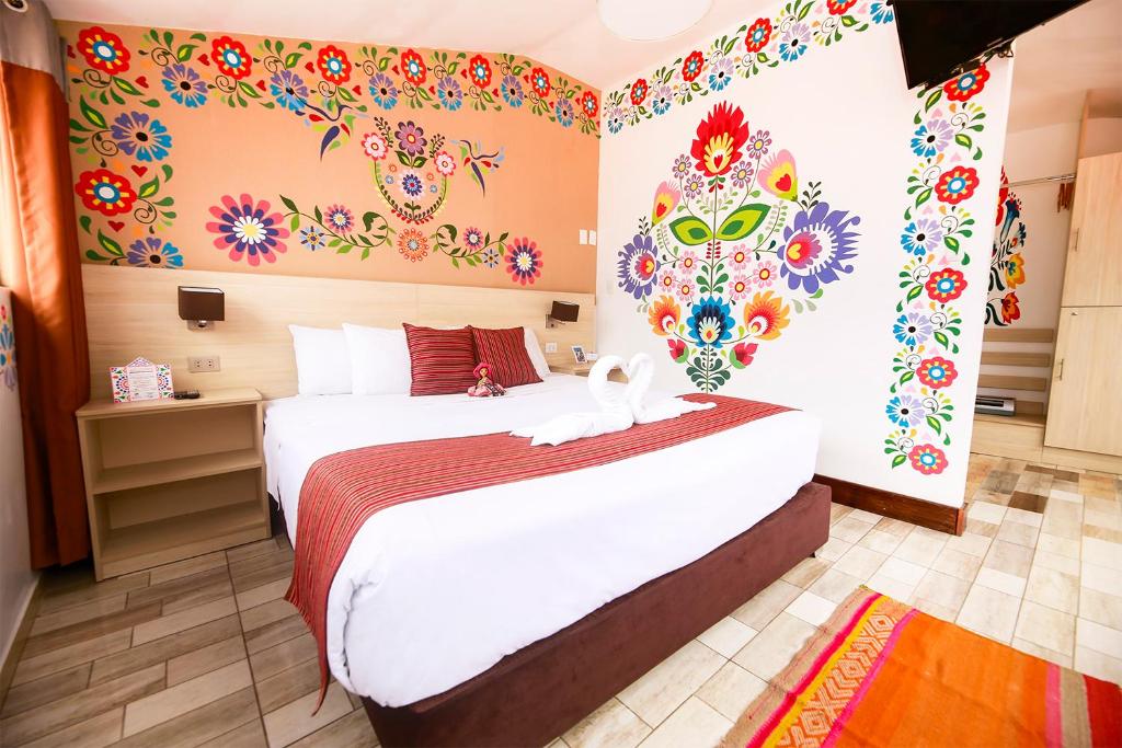 a bedroom with a large bed with flowers on the wall at Mayu Boutique Hotel in Cusco