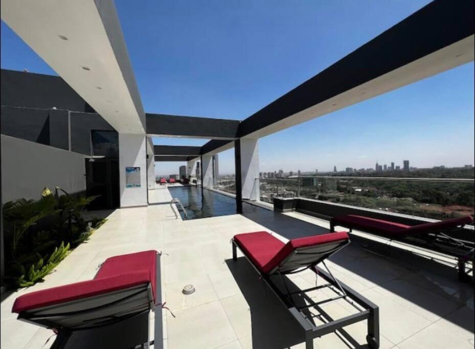 a balcony with red chairs and a view of the city at Luxury Westlands 2 bedroom Apt (Escada 403) in Nairobi