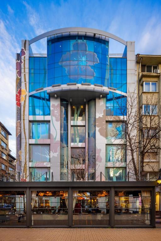 a tall glass building with a blue facade at Les Fleurs Boutique Hotel in Sofia