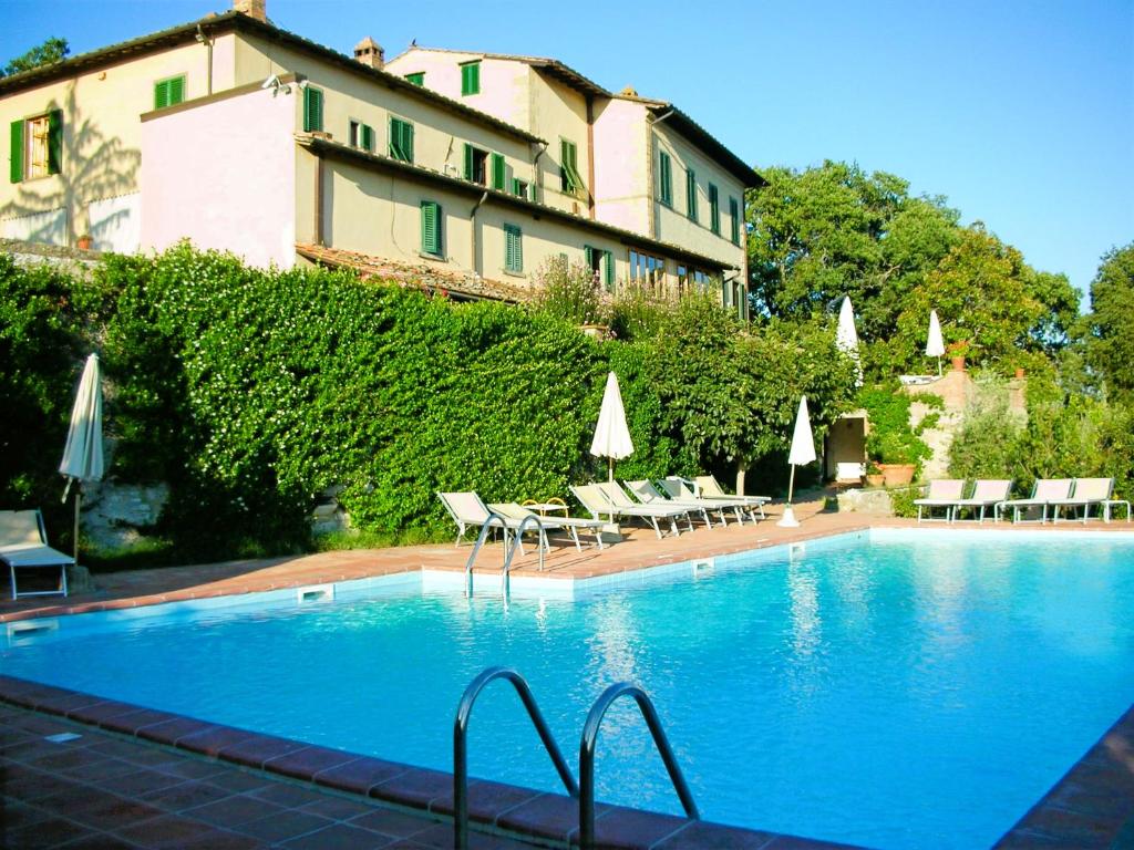 a swimming pool with chairs and umbrellas next to a building at Hotel Villa Casalecchi in Castellina in Chianti